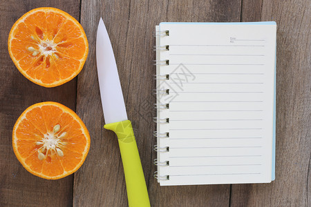 放在旧木制地板上的普通橘子和丙烯刀设计关于健康食品的概念图片