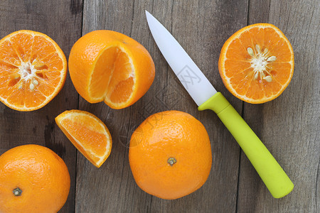 放在旧木制地板上的普通橘子和丙烯刀设计关于健康食品的概念图片