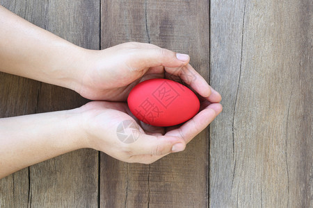 一枚鸡蛋在木板背景上手里握着一枚红色鸡蛋背景