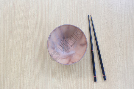 在设计概念食物的木本背景上黑筷子和碗放在顶层视线上图片