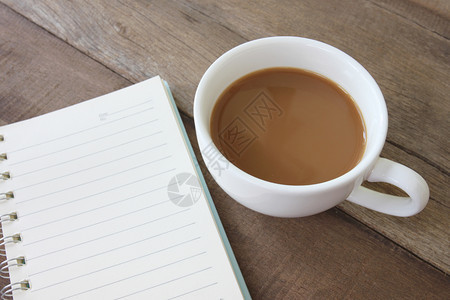 白咖啡杯和空书在木制地板上和饮料的概念图片