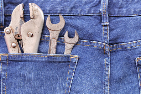 蓝牛仔裤的后口袋和旧扳手工具生锈设计在你的劳动日概念图片