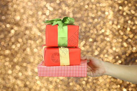 圣诞概念的红礼物盒手握着里面有金色模糊的布基背景用来设计你的工作图片