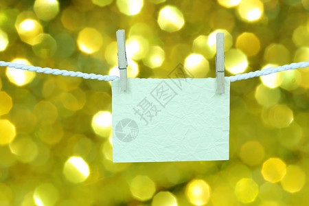 空白纸挂在衣服线上黄色bokeh背景上用于设计您的圣诞概念图片