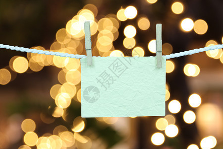 空白纸挂在衣服线上光博基背景上用于设计您的圣诞概念图片