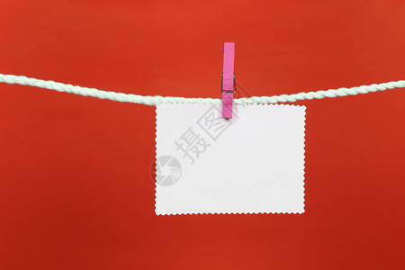 空白便条纸挂在衣着线上并有带红色背景的复制空间供您在工作概念中设计图片