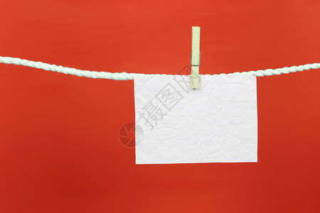 空白便条纸挂在衣着线上并有带红色背景的复制空间供您在工作概念中设计图片