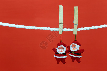 圣诞挂圣诞老人娃挂在衣绳上并有复制空间红色背景设计你的工作概念背景