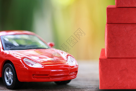 红玩具车和礼物盒放在木地板上圣诞礼物的概念图片