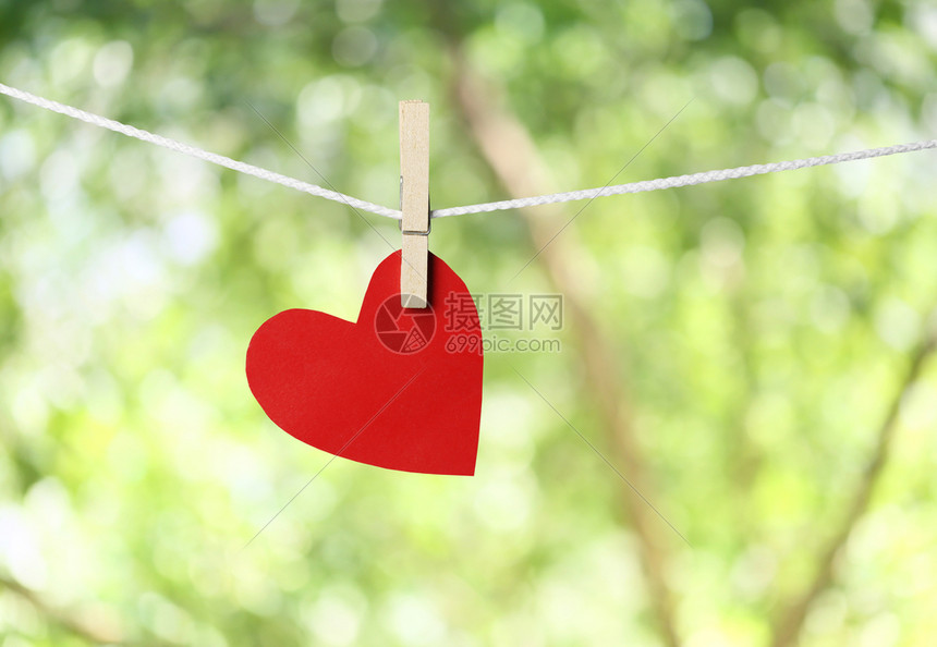 红纸心挂在绳子上情人节的概念和绿色bokeh背景图片
