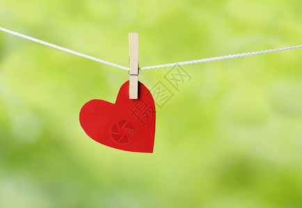 红纸心挂在绳子上情人节的概念和绿色bokeh背景图片