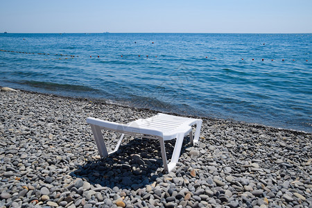 Chaise休息室在海岸线旁的一个石滩上为白色Chaise休息室在海边为白色Chaise休息室在海岸线旁的一个石滩上为白色图片