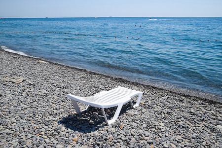 Chaise休息室在海岸线旁的一个石滩上为白色Chaise休息室在海边为白色Chaise休息室在海岸线旁的一个石滩上为白色图片
