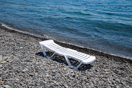 飞弹Chaise休息室在海岸线旁的一个石滩上为白色Chaise休息室在海边为白色Chaise休息室在海岸线旁的一个石滩上为白色背景