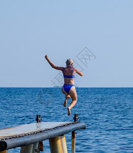 穿蓝色比基尼的漂亮女孩从码头跳到水里海图片
