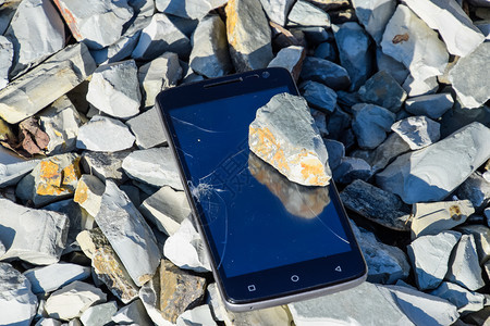 碎裂的电话在岩石上玻璃智能手机上碎裂的岩石智能手机坠落并毁碎裂的电话在岩石上玻璃一块石头上碎裂的图片