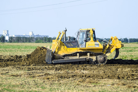 俄罗斯TemryukTemryuk2015年7月日带有附凝胶的黄色拖拉机在地面平整有关排水系统的实地工作图片