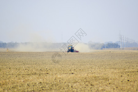 俄罗斯TemryukTemryuk2015年7月9日拖拉机在田里骑马把肥料放入土壤干拖拉机车产生的尘云耕田之后的肥料拖拉机在田里图片
