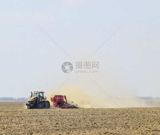 俄罗斯TemryukTemryuk2015年7月9日拖拉机在田里骑马把肥料放入土壤干拖拉机车产生的尘云耕田之后的肥料拖拉机在田里图片