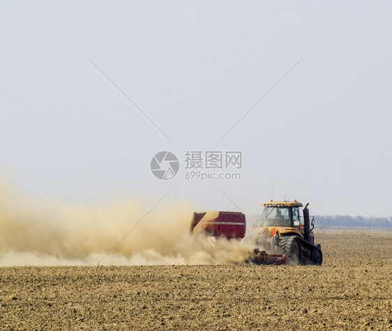 俄罗斯TemryukTemryuk2015年7月9日拖拉机在田里骑马把肥料放入土壤干拖拉机车产生的尘云耕田之后的肥料拖拉机在田里图片