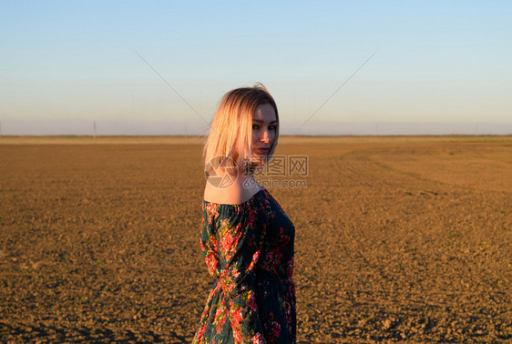 穿着日落背景的红黑礼服女人图片