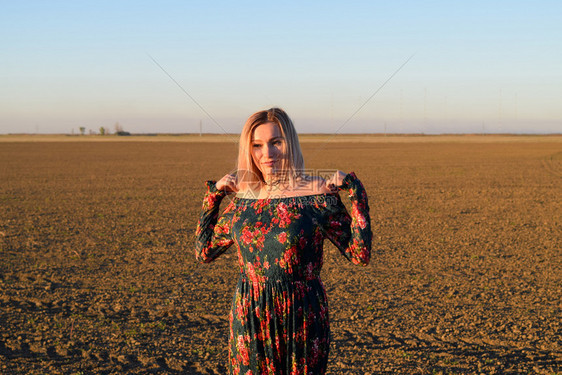 穿着日落背景的红黑礼服女人图片