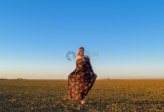 穿着日落背景的红黑礼服女人图片