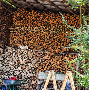 在屋顶下面的木丛中有的桩有一堆柴在屋顶下面的木棚里有柴的桩一堆柴图片