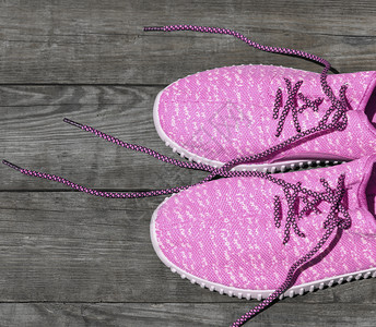 粉红色纺织运动鞋顶视图在木板底灰色背景上带不开丝的粉红色拖鞋图片