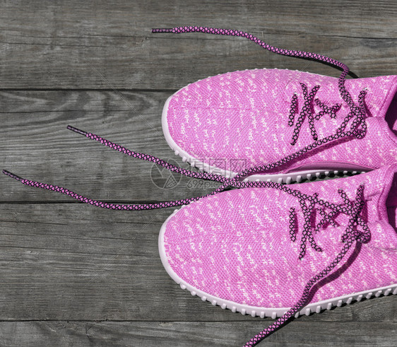 粉红色纺织运动鞋顶视图在木板底灰色背景上带不开丝的粉红色拖鞋图片