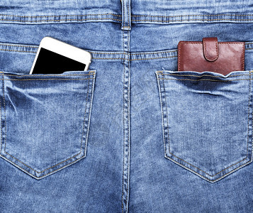 棕色皮钱包和白色智能手机在蓝牛仔裤后口袋中空黑屏幕关上图片