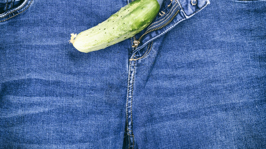 绿色新鲜黄瓜躺在蓝色牛仔裤上整身图片素材