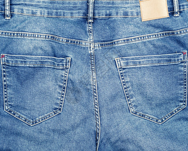 蓝色牛仔裤背面有口袋和皮革标签全框背景图片