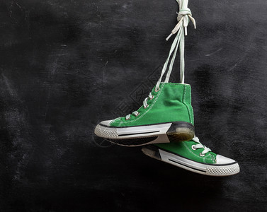 黑木背景复制空间上挂着的一对穿戴绿色纺织运动鞋图片