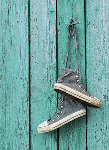 一对非常破旧的黑色纺织运动鞋挂在钉子上绿色的破旧木本底图片