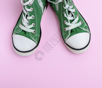 粉红背景的一对绿色儿童鞋顶部视图图片