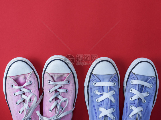 两对穿戴的纺织运动鞋红色背景顶视图复制空间上有白色带子图片