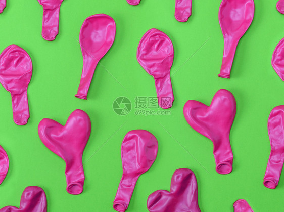 绿色背景下许多被吹散的橡皮粉红色气球图片