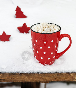 带有白波卡点的陶瓷红色杯子雪中加热巧克力和棉花糖背景图片