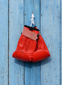 红色皮拳击手套挂在蓝色木墙上的钉子图片