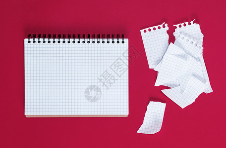 在一个单元格中打开笔记本在红色背景空的撕破工作纸上打开笔记本图片