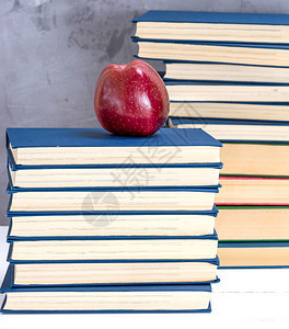 满的红苹果放在一堆蓝色封面的书上图片