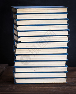 棕色木制桌子上蓝封面的大堆书背景图片