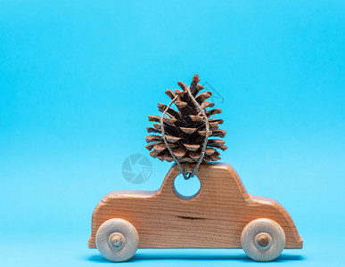 木制玩具车顶上有个松锥蓝底圣诞背景图片