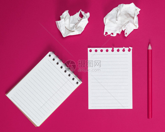 张开笔记本上面有白的床单和粉红色背景的纸图片