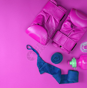粉红色背景空间抽象体育背景的一对皮粉色拳击手套蓝纺织品绷带和水瓶图片