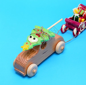 木童的汽车配有焦拉梅节的葡萄酒拉着雪橇蓝色背景的礼物图片