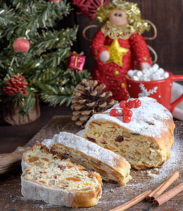 斯托伦是欧洲传统蛋糕有坚果和罐头水的欧洲传统蛋糕用冰糖粉尘在棕色木板上切成碎片图片