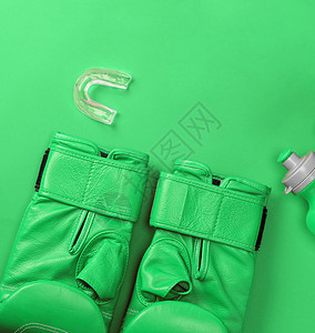 在背景空间抽象体育背景上戴一副绿色拳击手套和一瓶水图片