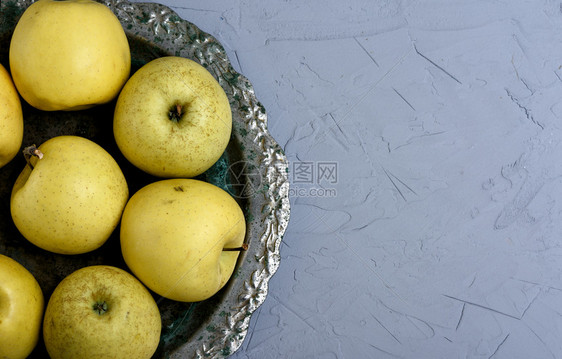 在灰色背景复制空间的铁板上成熟新鲜黄苹果图片